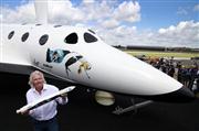 ２０１２年７月、英南部ファンボローで開かれた航空ショーで、一般人向け宇宙旅行用の機体「スペースシップ２」のレプリカの前で記者発表を行うリチャード・ブランソン氏。手に持っているのは、小型衛星の打ち上げ事業に使う「ランチャーワン」の模型（ＡＰ）