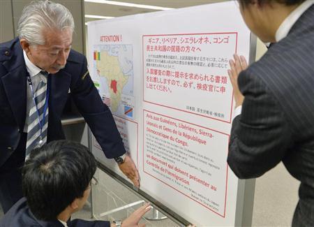 成田空港で、入国者に向けたエボラ出血熱対策のポスターを張る検疫所職員＝２０１４年１０月２８日、千葉県成田市（共同）