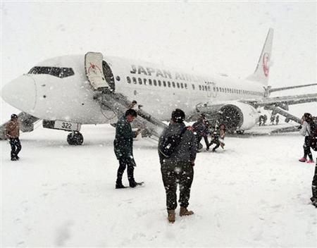 右エンジンから出た煙が客室内に流入した日本航空の旅客機から緊急脱出する乗客ら＝２３日午後、新千歳空港（乗客提供）