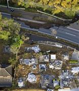 地震で陥没した道路や倒れた墓石＝１５日午前６時５４分、熊本県益城町