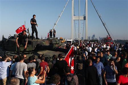 １６日、トルコ・イスタンブールのボスポラス海峡に架かる橋の上に集まった市民と戦車の上に立つ警官（ゲッティ＝共同）