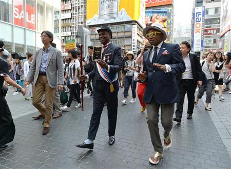 心斎橋筋商店街を練り歩いたコンゴからやってきた「世界一おしゃれで平和な紳士」といわれる「サプール」。手前右から（サプール名で）イバラ・ルノーさん、イヴ・サンローランさん＝大阪市中央区（南雲都撮影）