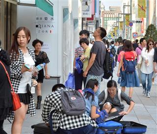 路上に座り込んでスーツケースに買った商品を詰め込む中国人旅行客＝東京・銀座の中央通り（撮影・三尾郁恵）