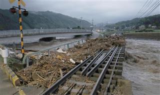 流木などで覆われた、大雨の影響で増水した福岡県添田町の彦山川に架かる線路＝５日午後７時４１分