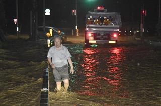 大雨の影響で冠水した福岡県朝倉市の道路を歩く人＝５日午後１１時１８分