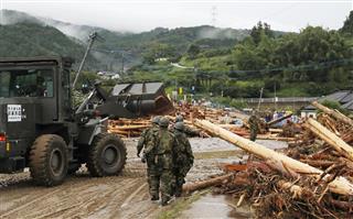 道路をふさぐ流木の撤去作業をする自衛隊員＝６日午前７時８分、福岡県朝倉市