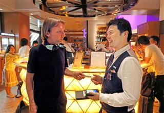 東京・渋谷の南欧料理店「ザ・リゴレット」のバーでクレジットカードを差し出すスウェーデン人客（左）＝９月中旬