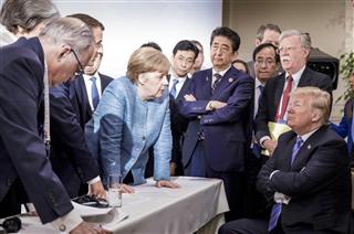 ９日、Ｇ７サミットでトランプ米大統領（右端）に向かい身を乗り出すドイツのメルケル首相（中央左）と、腕を組む安倍首相＝カナダ・シャルルボワ（ＵＰＩ＝共同）