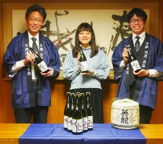 新しいラベルの日本酒「英勲鬼ころし」を手に取る齊藤社長（左）と池川さん（中央）＝京都市左京区