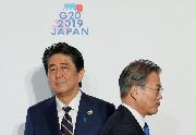 ６月、Ｇ２０大阪サミットで握手した後、すれ違う韓国の文在寅大統領（右）と安倍首相＝大阪市（ロイター）