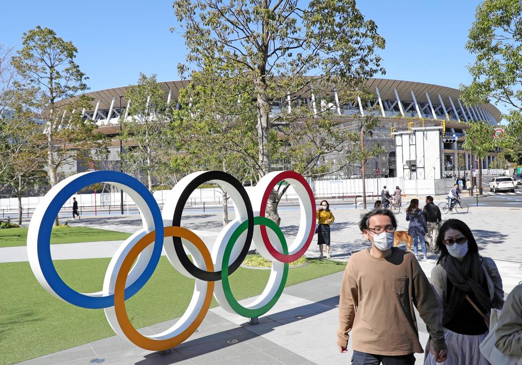 新国立競技場の前をマスク姿で歩く人たち＝東京都新宿区（撮影・桐原正道）