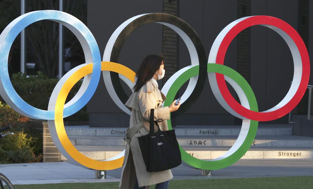 五輪マークのモニュメントとマスク姿の人＝３月２４日午後、東京都新宿区