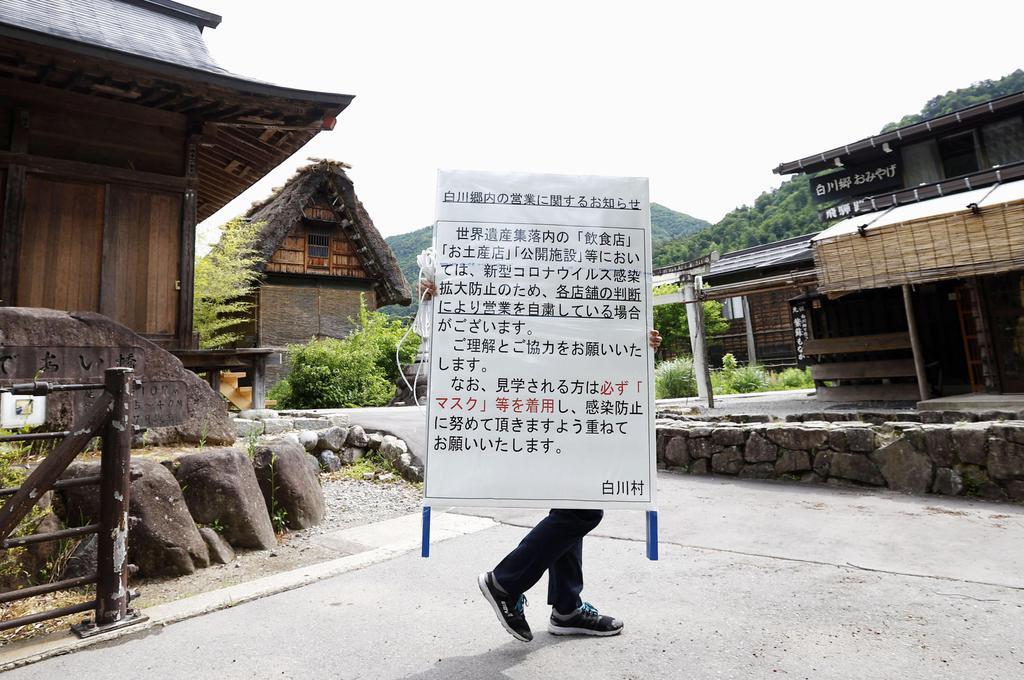 閉鎖が解除された岐阜県白川村の白川郷の合掌造り集落。中央は新型コロナウイルスの感染予防などを呼び掛けるため設置される看板＝１日午前