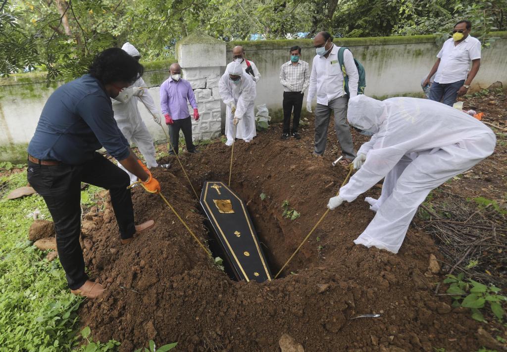 インド・ムンバイで新型コロナ感染症による死者のひつぎを下ろす人々＝６月（ＡＰ）