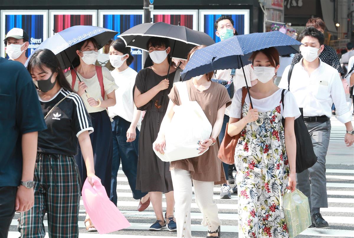 厳しい暑さのなか、日よけの傘を手にマスク姿で歩く人たち＝７日午後、大阪市中央区（鳥越瑞絵撮影）