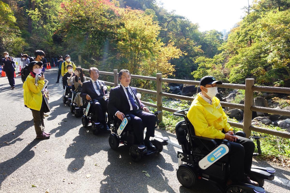 甲府市の景勝地、昇仙峡の渓谷沿いの道を運行する観光モビリティ「PiiMo」を試乗する長崎幸太郎・山梨県知事（写真右から2番目）＝11月3日、山梨県甲府市（SankeiBiz編集部）